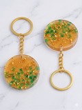 Handmade Resin Round Disc Keychain – Amber Orange with Green Glitter & Gold-Tone Flakes